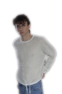 a young man wearing a white sweater and jeans